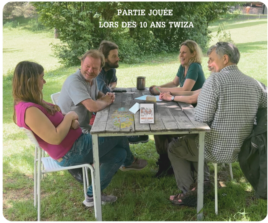 5 personnes à l'extérieur autour d'une table jouant a habitats heureux